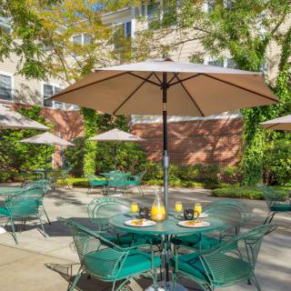 Sunny patio with tables, chairs, and large umbrellas for outdoor relaxation.