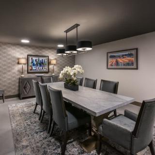 A modern dining room with a large table, elegant chairs, and stylish lighting.