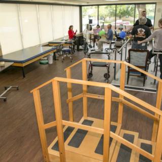A rehabilitation center equipped with exercise equipment and therapy areas where people are engaged in physical therapy activities.