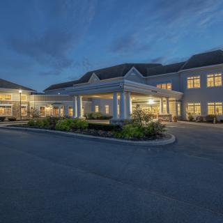 A well-lit building entrance during the evening with surrounding landscaping.