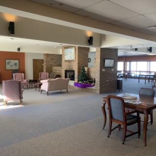 A spacious lounge area with comfortable seating, tables, and a fireplace.