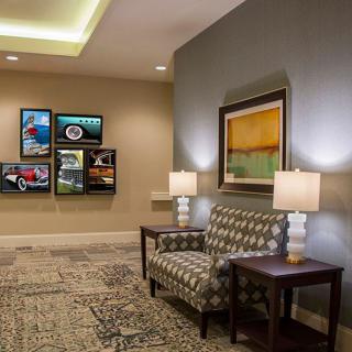 A well-decorated lobby featuring a patterned sofa, side tables with lamps, and various artworks on the walls.
