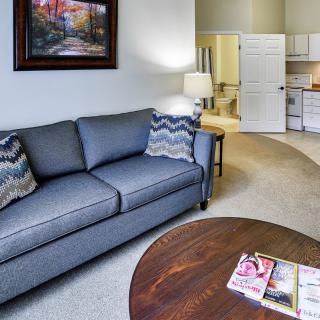 A cozy living room with a blue sofa, decorative cushions, and a wooden coffee table.