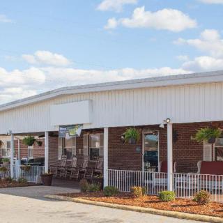 A commercial building with outdoor seating and hanging plants on a sunny day.
