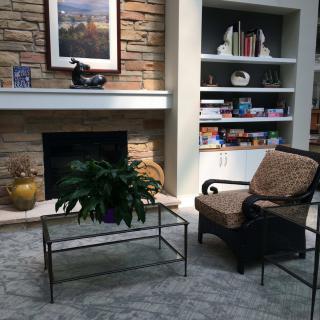Cozy living room with a fireplace, armchair, and bookshelves.