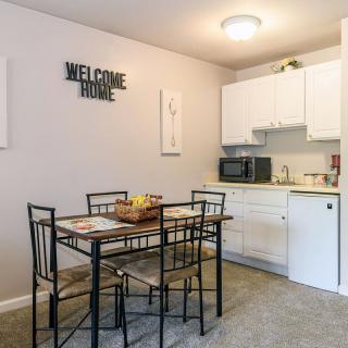 A cozy kitchenette with a dining table and chairs, featuring modern decor and white cabinetry.