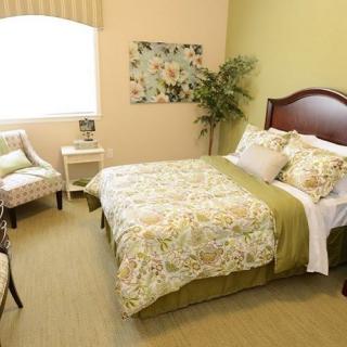 A cozy and well-decorated bedroom with a bed, armchair, and potted plant.