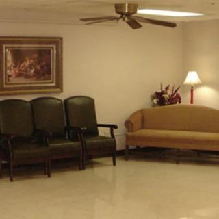 A small waiting room with chairs, a sofa, and a lamp.