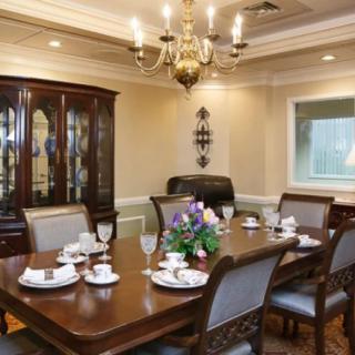 An elegant dining room with a large wooden table set for a meal, featuring a chandelier and china cabinet.