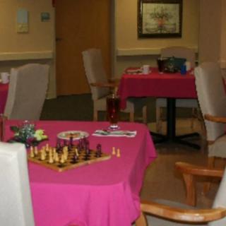 A cozy game room with tables covered in pink tablecloths, one featuring a chess set.