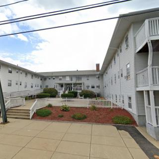 Exterior view of a residential apartment building with landscaped surroundings and balconies.