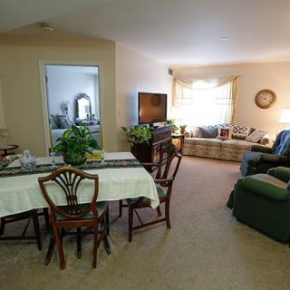 A cozy living room and dining area with a table set up for meals, comfortable seating, and indoor plants enhancing the decor.