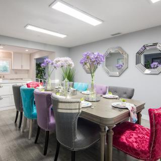 A modern dining room with a colorful array of chairs and a well-set table adorned with flowers.