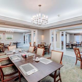 An elegant dining area featuring chandeliers, neatly arranged tables, and comfortable seating.