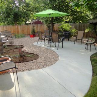 A backyard patio with outdoor seating, surrounded by a gravel path and greenery.
