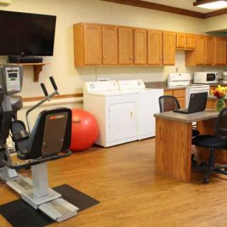 A multifunctional room combining a home gym, laundry area, and kitchen space.
