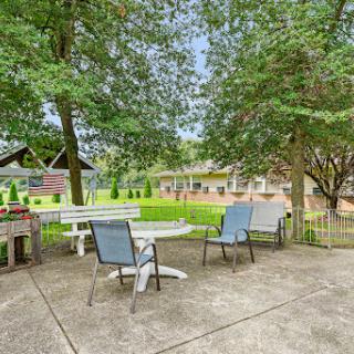 A serene outdoor patio area surrounded by trees, featuring a table and chairs for relaxation.