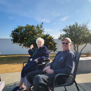 Two people sitting outside enjoying a sunny day in the garden.