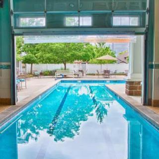 A serene indoor swimming pool with an open view to the outdoor area, surrounded by lush greenery.
