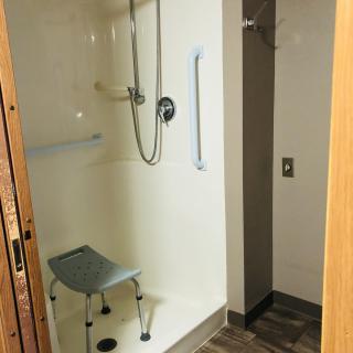 An accessible walk-in shower with a chair and grab bars for safety.