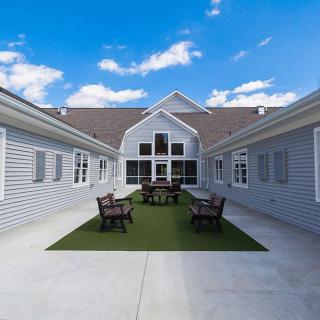 A courtyard with outdoor seating surrounded by a modern building under a blue sky.