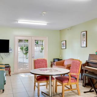 A cozy living room with a piano, television, table, and chairs.