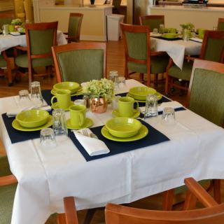 A neatly set dining table with green tableware in a restaurant setting.