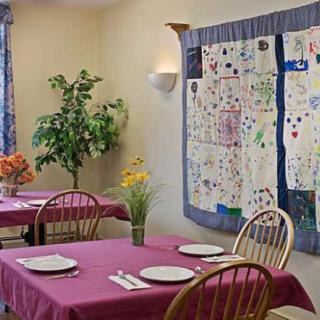 A cozy dining area with neatly set tables, wall art, and potted plants.