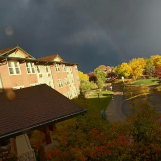 A picturesque autumn scene with colorful trees under a dramatic cloudy sky.