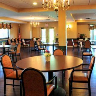 A spacious dining area with multiple tables and chairs, illuminated by chandeliers.