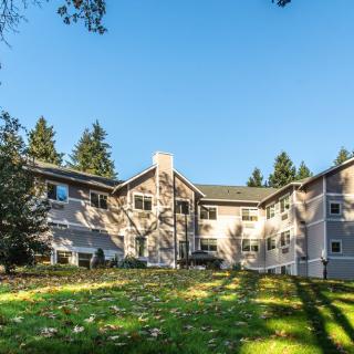A residential apartment building surrounded by greenery and trees on a sunny day.