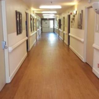 A long, well-lit hallway with doors on either side and wooden flooring.