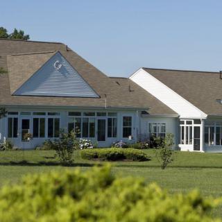 A large residential house with a well-maintained lawn under a clear blue sky.