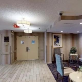 A lobby with seating and decor, featuring an exit sign and overhead lighting.