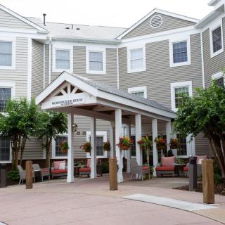 A residential building with a welcoming porch entrance surrounded by trees.