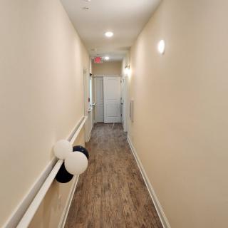 A long hallway with wooden flooring and decorations, featuring black and white balloons on the side.