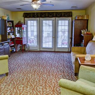 A cozy living room with comfortable seating, bookshelves, and large windows providing natural light.