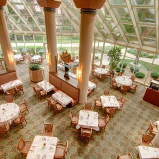 A spacious and elegant restaurant interior with natural light streaming through a glass ceiling.