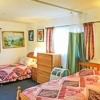 A cozy bedroom with twin beds, decorated with paintings and well-lit by a window.