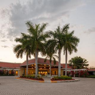 A tropical building surrounded by palm trees at sunset.