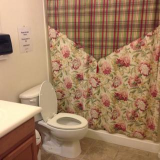 A bathroom with a floral and plaid shower curtain, toilet, and sink.