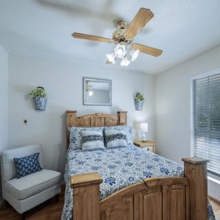 A cozy bedroom with a wooden bed, patterned bedding, and a ceiling fan.