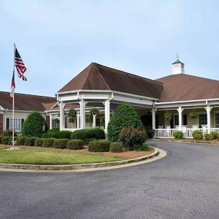 A well-maintained building with a circular driveway, surrounded by landscaped gardens and featuring an American flag.