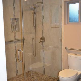 A modern bathroom with a glass-enclosed shower and toilet.