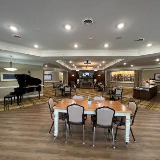 A spacious, elegantly designed living area with a grand piano and a large dining table.
