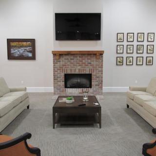 A cozy living room with a brick fireplace, two sofas, and a TV mounted above.