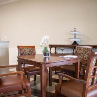 A cozy living room setup featuring a wooden table surrounded by chairs and decorated with an orchid centerpiece.