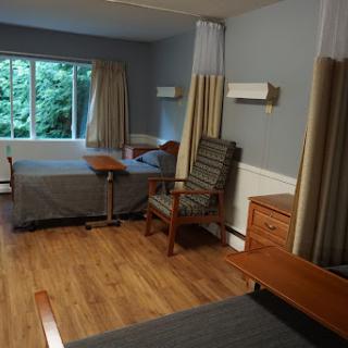 A spacious and well-furnished bedroom featuring two beds, a seating area, and large windows letting in natural light.