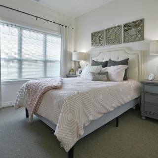 A cozy and elegantly decorated bedroom with soft lighting and large windows.