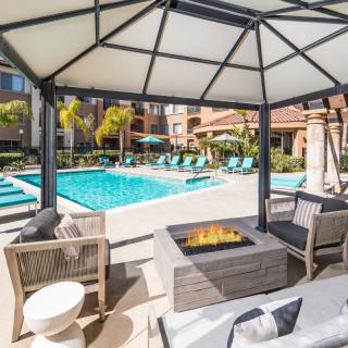 A luxurious poolside lounge area featuring a gazebo and fire pit.